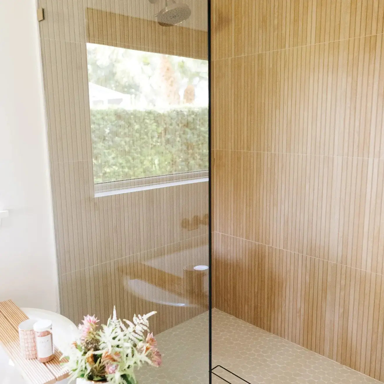 Modern bathroom with glass shower, wood-like tile walls, and a clean, minimalistic design.