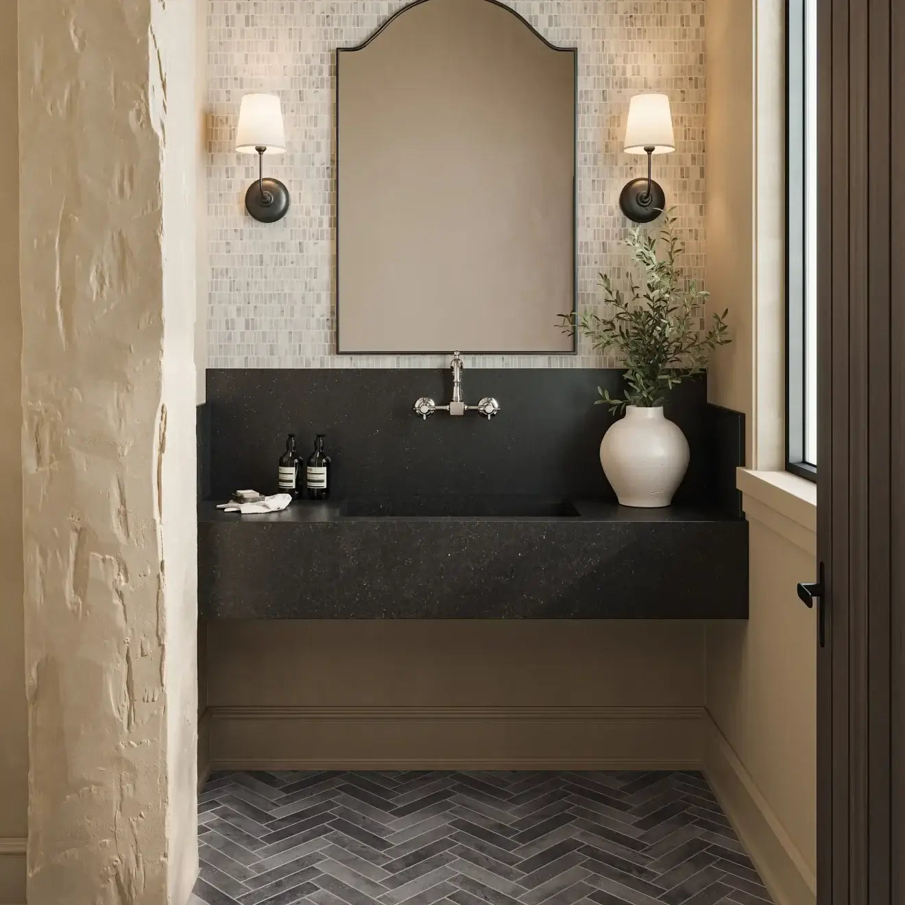 Stylish modern bathroom featuring a sleek black countertop, wall sconces, and mosaic tile flooring.