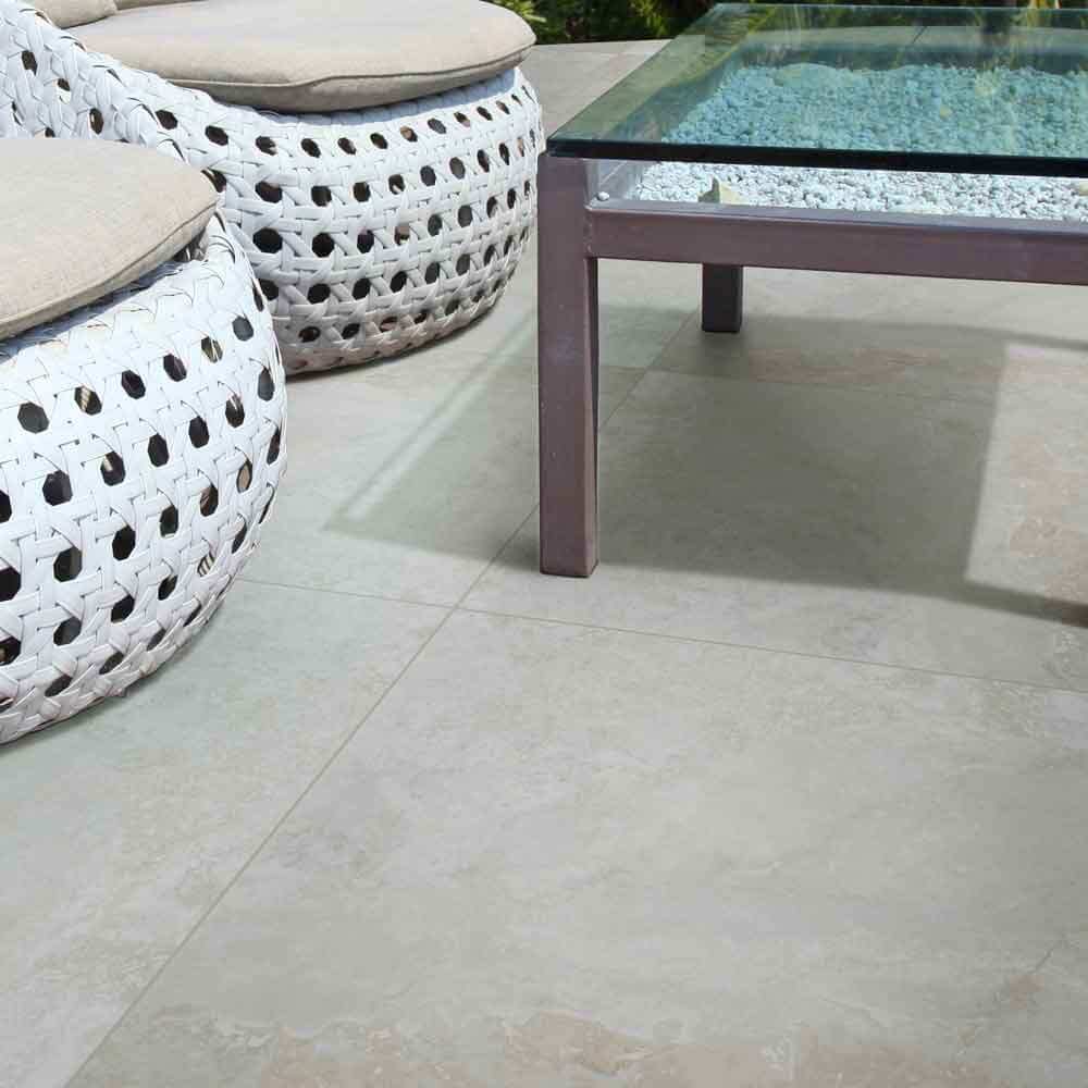MSI Argento Travertino 24x24 porcelain paver in outdoor living space with woven chairs and glass table.