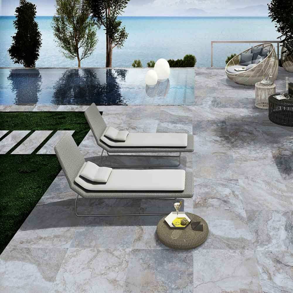Outdoor area featuring MSI Argento Travertino Porcelain Pavers with loungers and a scenic pool view.