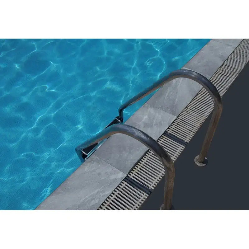 Close-up of a pool with Atlantic Blue tumbled marble coping and metal handrails, showcasing poolside design elegance.