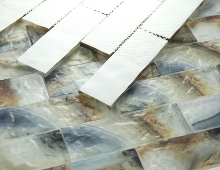 Art Onyx Mauna 11.75 x 11.75 glass tile in a linear brick pattern with shades of blue, brown, and beige.