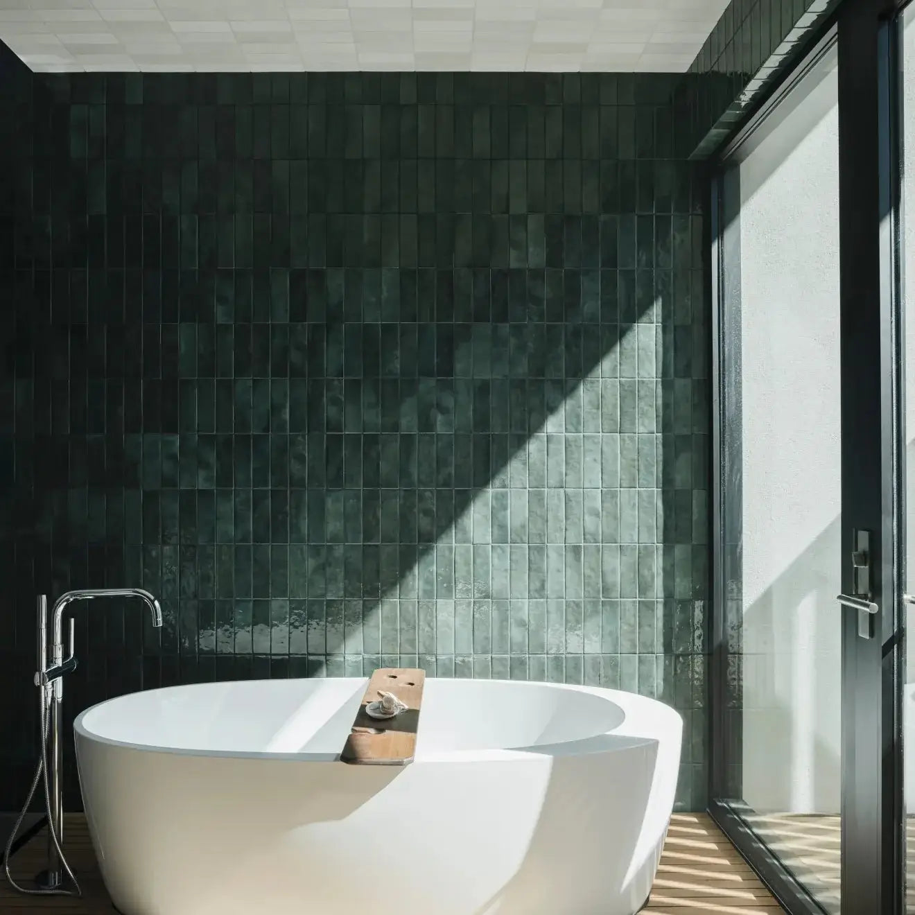 Modern bathroom featuring Cloé glossy green ceramic tiles and a freestanding white bathtub.