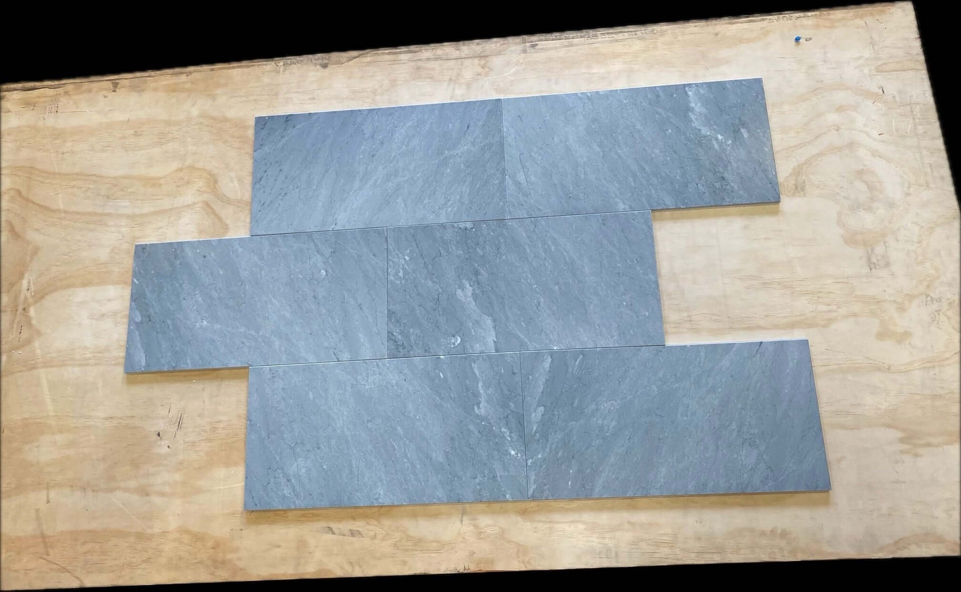 12x24 Bardiglio Imperiale Marble Tile pieces on wood surface showcasing unique bluish-grey tones and elegant veining.
