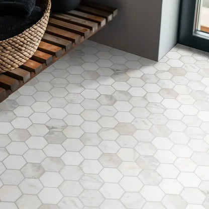 Honed white hexagon marble mosaic tile flooring in a modern interior setting with wooden shelf.