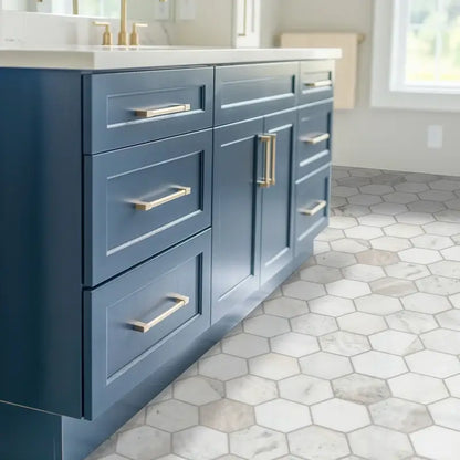 Modern blue kitchen cabinet with gold handles over elegant hexagon marble floor tile.