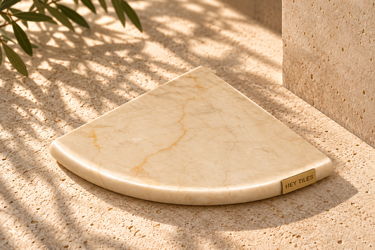Crema Marfil marble shower corner shelf with brass Hey Tiles logo — artistic photo 1