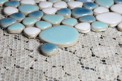 Close-up of blue and white pebble mosaic tiles on a textured surface, perfect for stylish decor and pools.